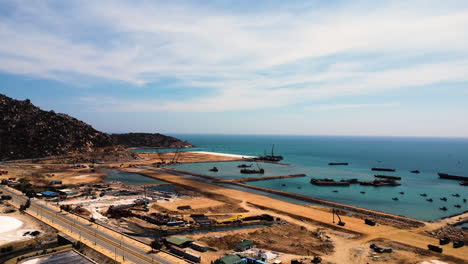 Construction-site-in-Ca-Na-Vietnam,-harbour-port-building-in-progress,-aerial-view-scenic-natural-seascape-asiatic-coastline-with-crane-and-excavator