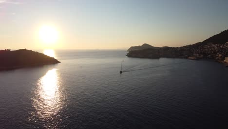 Aerial-shot-at-sunset-of-the-Adriatic-Sea-and-Dubrovnik-coast-with-a-boat