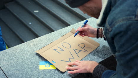 Protester-preparing-placard-against-war-in-Ukraine-at-a-rally,-Prague