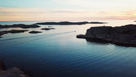 Drone-flying-towards-motorboat-over-open-waters-during-sunset