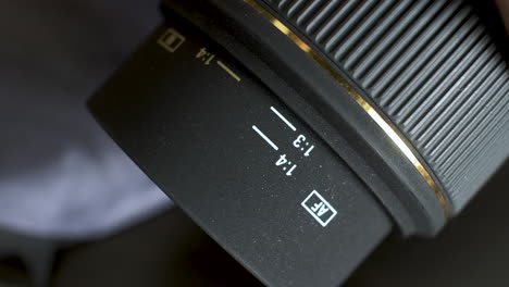 A-close-up-shot-of-a-fixed-aperture-DSLR-camera-lens,-the-focus-ring-rotating-as-it-extends-the-core-of-the-lens-which-is-marked-with-a-distance-scale-and-used-as-an-aid-to-focus-the-subject