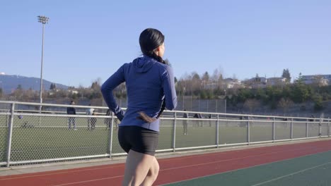 Fit-athletic-woman-running-on-track-outdoors-gimbal-shot