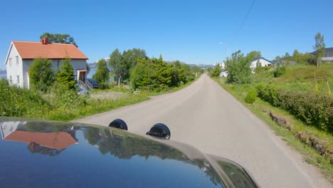 Hood-view-driving-car-through-Norwegian-village-with-narrow-highway,-Northern-Norway,-Slow-motion-60p