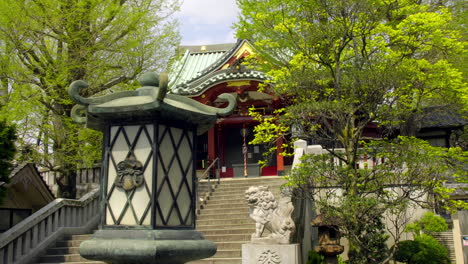 TOKYO,-JAPAN-circa-April-2020:-men-climbing-up-the-stairs-to-pray-at-traditional-Japanese-temple,-approach-with-authentic-lantern-in-peaceful-zen-style-garden-on-a-sunny-spring-day