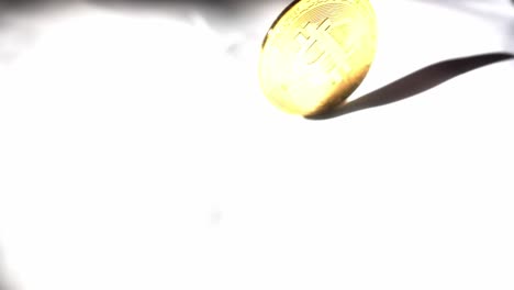 Hand-Dreht-Bitcoin-Aus-Massivem-Gold,-Bis-Es-Stoppt-Und-Flach-Auf-Weißen-Hintergrund-Fällt