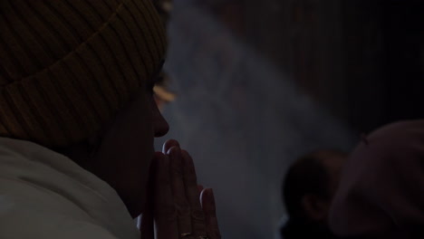 Eine-Frau-Legt-Ihre-Hände-Zum-Gebet-Zusammen,-Während-Bei-Der-Beerdigung-Eines-Ukrainischen-Soldaten-Während-Der-Russischen-Invasion-Im-Land-Licht-Durch-Ein-Fenster-Fällt