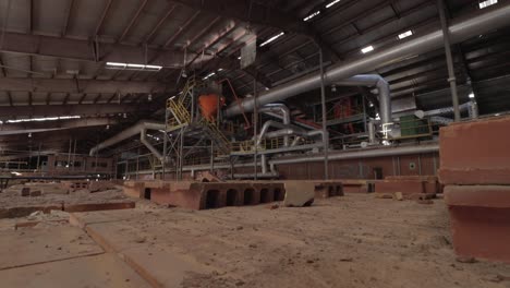 Slider-Footage-of-Machinery-and-Furnaces-in-an-Abandoned-Brick-Factory-with-Dust-Covered-Bricks-in-the-Foreground