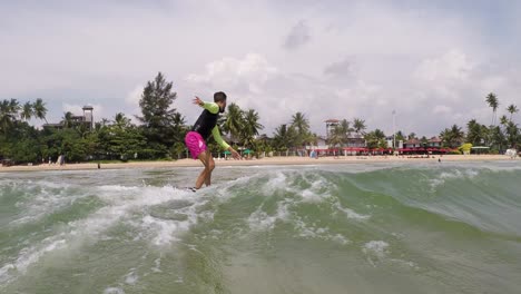 Athletic-Guy-Riding-Wave-On-surfboard-Competing-With-His-Friends-On-Lovely-Beach-Of-Weligama,-Sri-Lanka