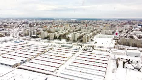Colorful-garage-box-doors-and-living-district-of-Kaunas-city-during-snowfall,-aerial-ascend-view