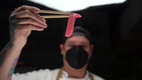 Lateinamerikanischer-Koch-Hält-Rosa-Frischen-Thunfisch-Für-Die-Zubereitung-Von-Sushi-In-Zeitlupen-Gesichtsmaske
