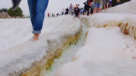 Static-close-up-of-a-person-walking-barefoot-on-the-shores-of-the-calcareous-rocks-of-Pamukkale,-Turkey