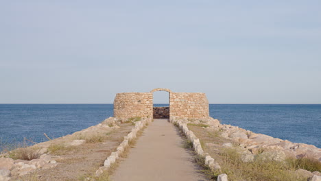 Wide-shot-of-a-ruined-fortification-located-on-the-coast-with-blue-sea-views-and-clear-skies