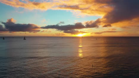 Drone-Reveal-of-Beautiful-Hawaiin-Ocean-Sunrise-with-Boats-Sailing-Over-Waikiki-Beach-In-Honolulu,-Hawaii
