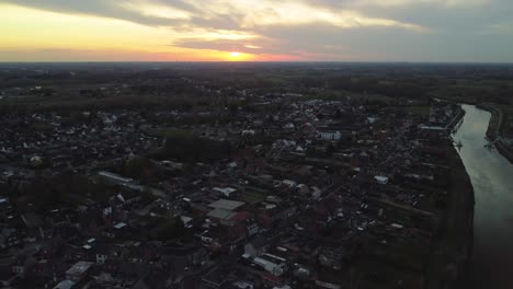 Truck-aerial-view-of-sunset-over-riverside-town-in-Belgium