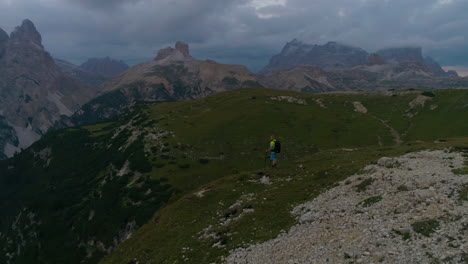 Aerial-view-hiker-overlooking-extreme-idyllic-Tre-Cime-South-Tyrol-quiet-grassy-mountain-range-landscape