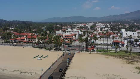 aerial-drone-of-cars-crossing-the-Stearns-Wharf-Pier-in-downtown-Santa-Barbara-on-a-sunny-summer-day-in-California-with-large-mountains-in-the-distance