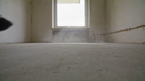 Wide-shot-of-sweeping-on-a-dusty-floor-with-and-old-broom