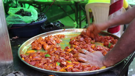 a-food-vendor-mixing-spices-in-meat