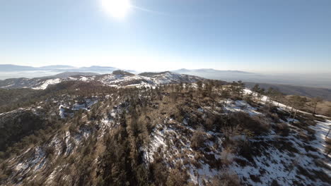 Revealing-a-snow-covered-mountains-landscape-with-an-FPV-drone,-descending-view