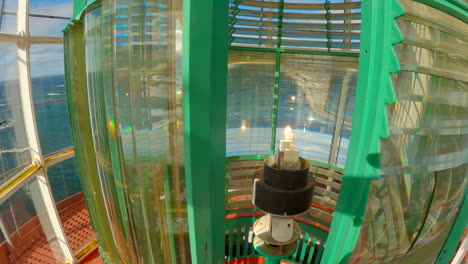 Static-inside-shot-of-the-lantern-room-of-a-lighthouse-during-a-bright-sunny-day-with-the-fresnel-lens-moving-by-the-lamp-light