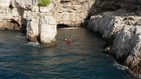 Vista-Aérea-De-Turistas-En-Kayak-Cerca-De-Acantilados-Y-Cuevas-En-Pula,-Istria,-Croacia---Disparo-De-Drones