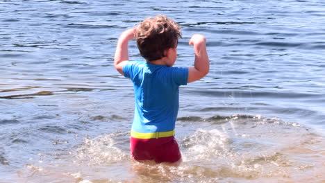 A-small-child-is-excited-to-splash-in-the-water-of-a-pond