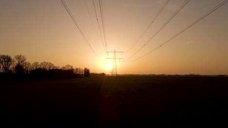 Dolly-motion-under-high-voltage-wires-during-Sunset,-Silhouette-of-Electric-tower