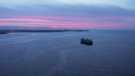 Scenic-purple-cloudy-sunset-at-bay-in-Iceland-with-large-cruise-ship-anchored,-aerial