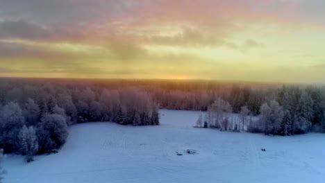 Misty-golden-sunset-over-snow-covered-landscape-in-freezing-winter