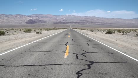 Cracked-heated-highway-crossing-Death-Valley,-Mojave-Desert,-California,-Forward-dolly-in-shot