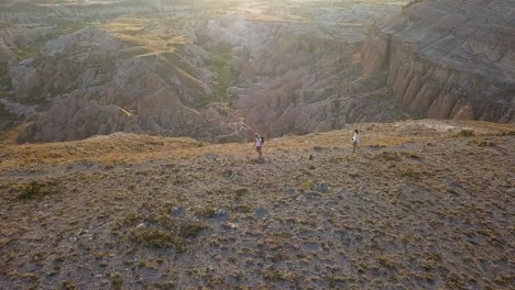 Orbiting-aerial-with-lens-flare:-Hikers-on-hoodoos-canyon-rim-trail