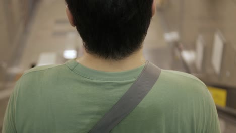Blick-Auf-Den-Rücken-Eines-Asiatischen-Mannes,-Während-Er-Die-Rolltreppe-Benutzt,-Um-Zur-U-Bahn-Station-Zu-Gelangen