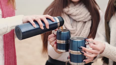 Girl-is-pouring-tea-into-metallic-mugs-of-her-girlfriends
