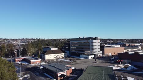 Kongsberg-Defence-and-Aerospace-headquarter-in-Norway---Manufacturer-of-missiles-and-advanced-military-weapon-systems---Ascending-aerial-watching-huge-office-building-with-logo-at-sunny-winter-day