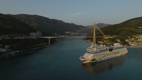 Crucero-Aidnova-Navegando-Linealmente-Desde-El-Pintoresco-Puerto-De-Dubrovnik,-Croacia,-Dron-Aéreo-De-5k