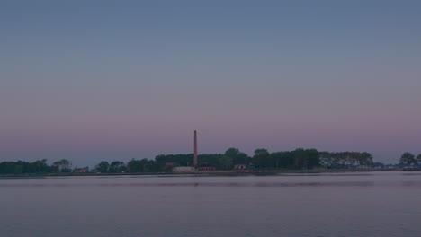 Wide-shot-of-Chimney-at-Hart-Island,-Solemn-burial-site-for-unidentified-dead,-from-the-water-in-the-evening