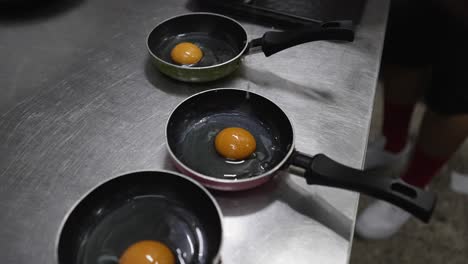 Chef-Rompiendo-Huevo-En-Una-Sartén-En-La-Cocina-Del-Restaurante,-Primer-Plano-En-Las-Manos