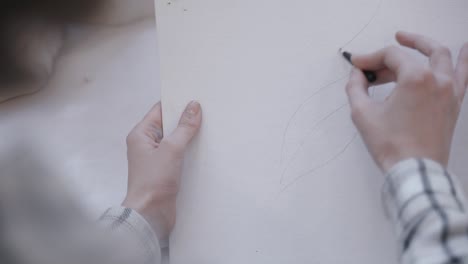 Artist-delicately-using-a-black-pencil-to-make-a-trace-on-paper-before-drawing