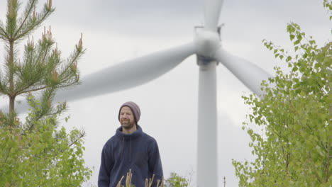 WIND-POWER---A-bearded-man-looks-at-wind-turbines-on-a-windy-day