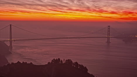 Static-shot-of-cloud-movement-over-red-and-yellow-sky-during-sunrise-in-timelapse-over-well-known-Golden-Gate-Bridge