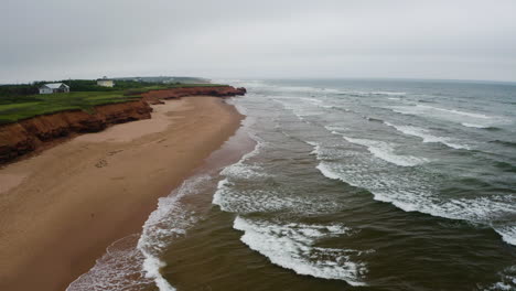 Aerial-view-of-the-waves-approaching-the-empty-Thunder-Cove-Beach-on-a-grey,-cloudy-day