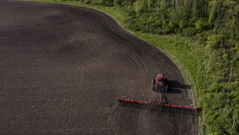 Aerial-shot-of-tractor-cultivating-large-unplanted-field
