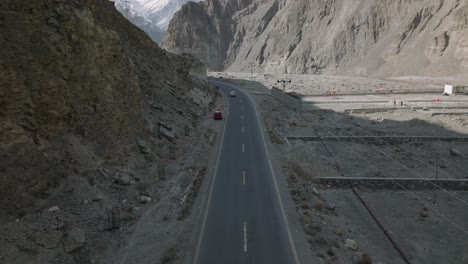 Auto-Fährt-Entlang-Der-Autobahn-In-Den-Horizont-Im-Hunza-Tal-Mit-Nach-Oben-Geneigtem-Blick-Auf-Schneebedeckte-Berge-Im-Fernen-Hintergrund
