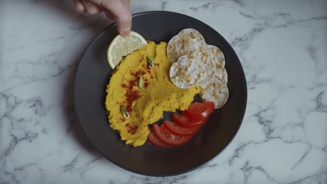 A-breakfast-plate-composed-of-tomatoes,-eggs-and-lemon-being-seasoned-with-salt