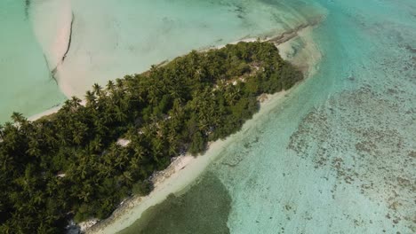 Drone-flight-over-the-Maldivian-coast-with-many-green-trees,-view-from-the-ocean-against-the-backdrop-of-a-stormy-sky