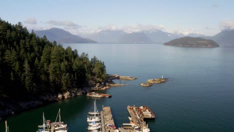 Barcos-Atracados-En-El-Centro-De-Aventuras-Marinas-De-Sewell-Con-Vistas-Panorámicas-De-La-Naturaleza-En-La-Bahía-De-Herradura,-Bc,-Oeste-De-Vancouver,-Canadá