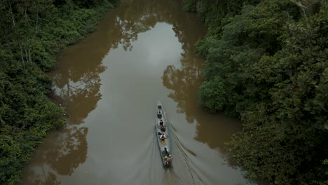 Small-Motorboat-Cruising-The-Amazon-River-With-Lush-Green-Vegetation---aerial-drone-shot