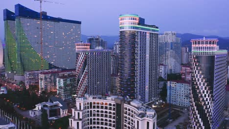 Vista-De-Drones-De-Rascacielos-De-Apartamentos-Iluminados-Al-Amanecer-De-La-Noche
