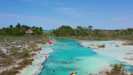 tourists-swimming-in-Los-Rapidos-in-Bacalar-Mexico-on-sunny-summer-day,-aerial