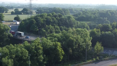 Aerial-view-across-British-woodland-countryside-with-vehicles-travelling-on-highway-background